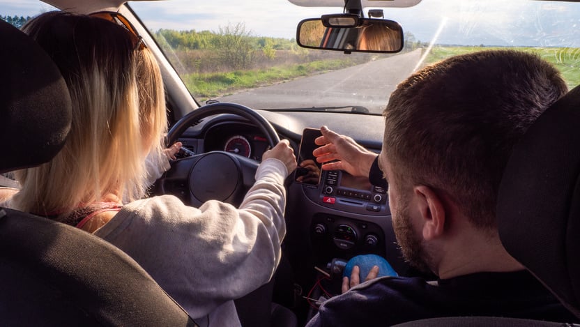 A driving instructor helps a woman learn how to drive a car. A woman is driving a car for the first time with an instructor and is very worried. Summer car driving training concept. Law exam.